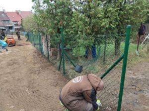 Muž instalující pletivové oplocení zahrady